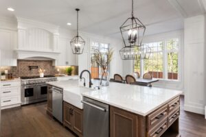 white kitchen with large kitchen island brown cabinets and modern metallic chandelier hanging lighting